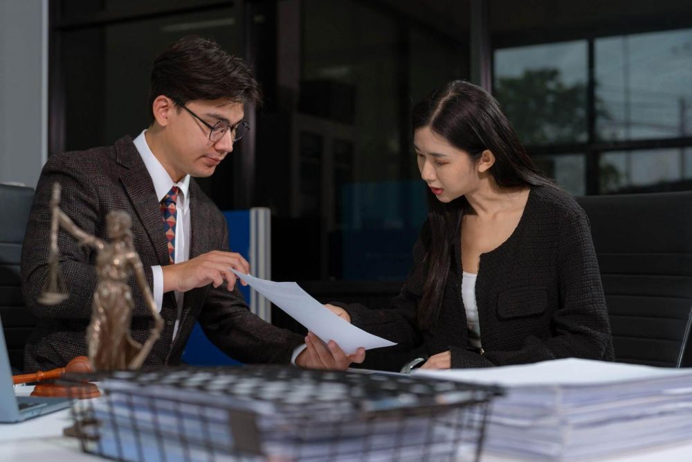 Two professionals reviewing documents at a desk in a modern office setting.