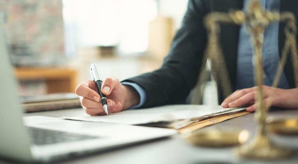 a person sitting at a desk with a laptop and a pen