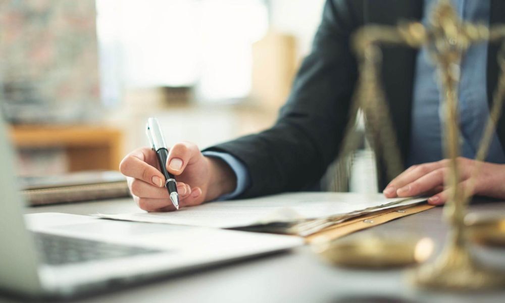 a person sitting at a desk with a laptop and a pen