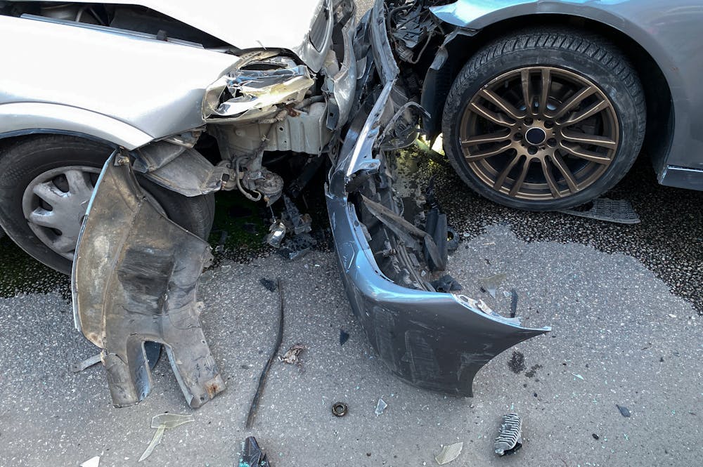 Types of Auto Accidents in Montana Our Firm Handles – Joyce, MacDonald, Haynes & Johnston Two cars are damaged and collided at an awkward angle, with crumpled metal and debris scattered. One car's front panel is bent, while the other shows significant front-end damage.